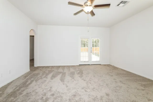 an empty room with windows and fan