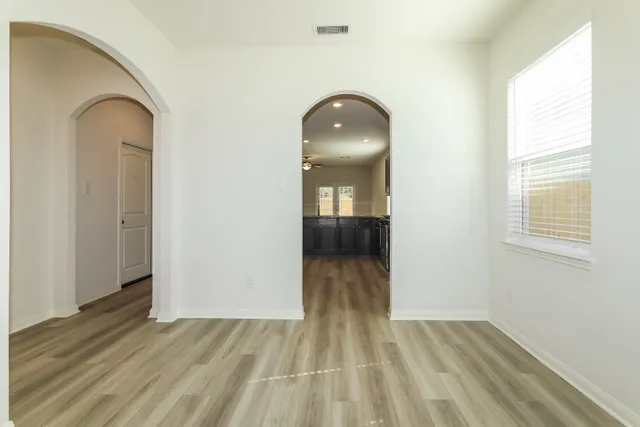an empty room with wooden floor and windows