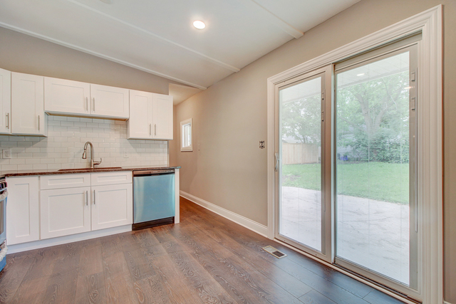 309 Audubon Road Streamwood, IL 60107 - Photo 13 of 25 a kitchen with granite countertop a refrigerator sink and white cabinets