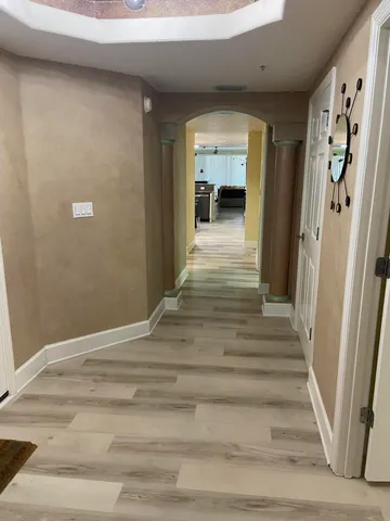 a view of a hallway to a livingroom with wooden floor and a ceiling fan