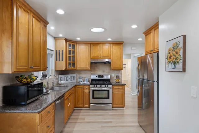 a kitchen with stainless steel appliances granite countertop a stove a refrigerator and a sink