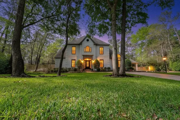 a view of a house with a big yard and large trees
