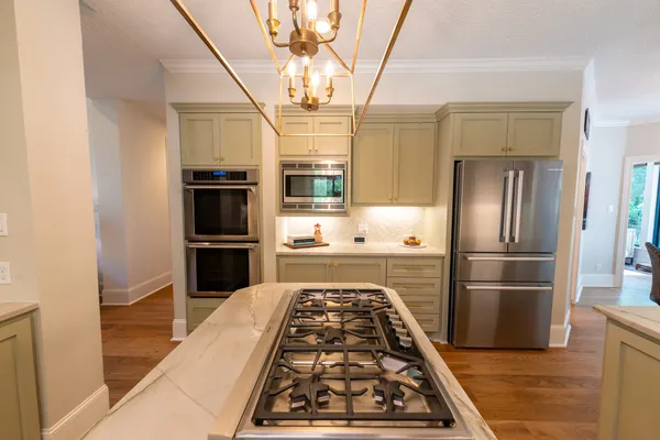 a kitchen with a stove a sink and wooden floor