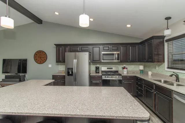 a kitchen with stainless steel appliances granite countertop a refrigerator a stove top oven a sink and dishwasher