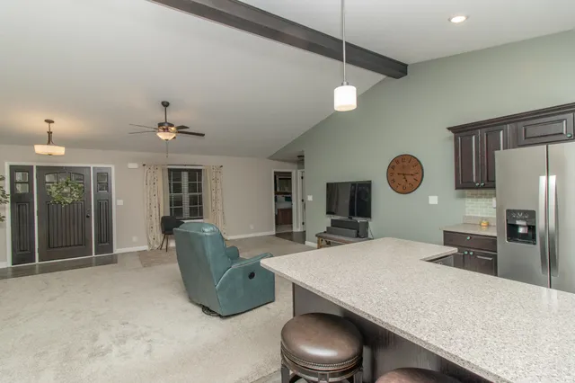 a living room with furniture a flat screen tv and kitchen view