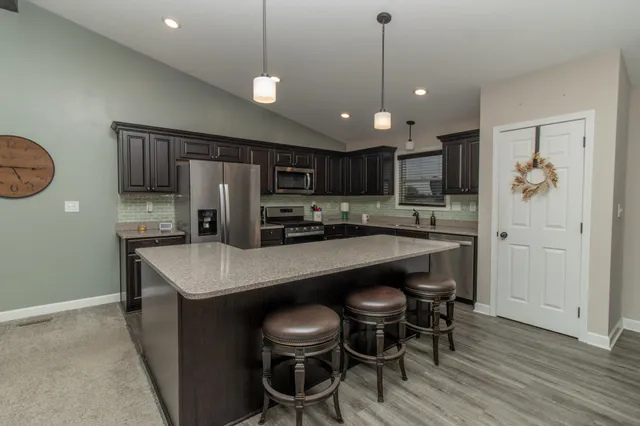 a kitchen with stainless steel appliances granite countertop a table chairs sink refrigerator and microwave