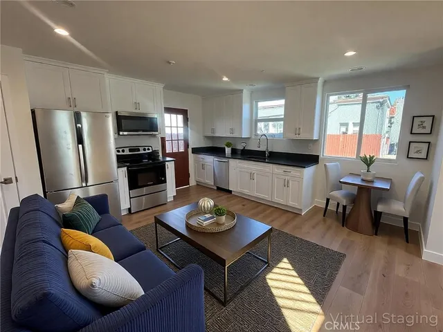 a living room with furniture a refrigerator and kitchen view