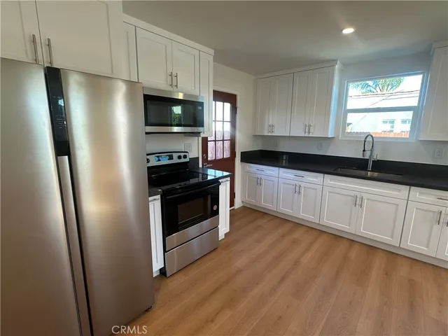 a kitchen with granite countertop a refrigerator stove and sink