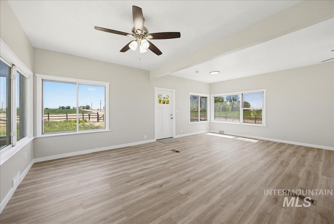 30013 Apple Valley Road Parma, ID 83660 - Photo 9 of 25 Spacious room featuring wood-finish flooring, ample natural light from multiple windows, a ceiling fan, and a light-colored wall palette
