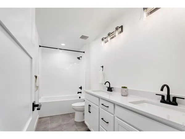 a bathroom with a double vanity sink toilet a shower and a mirror