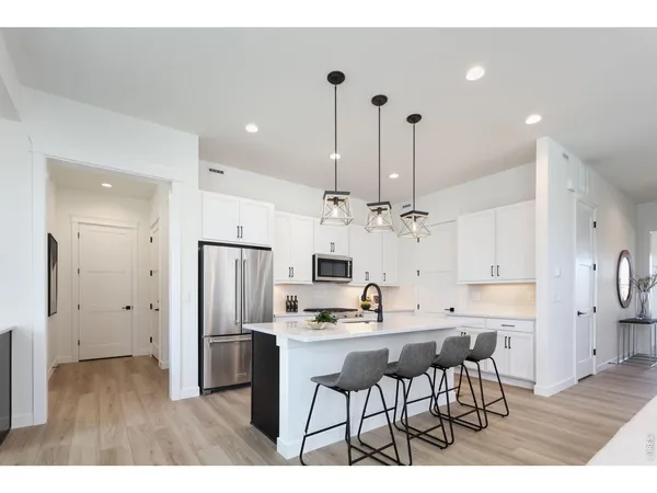 a kitchen with stainless steel appliances a dining table chairs refrigerator and microwave