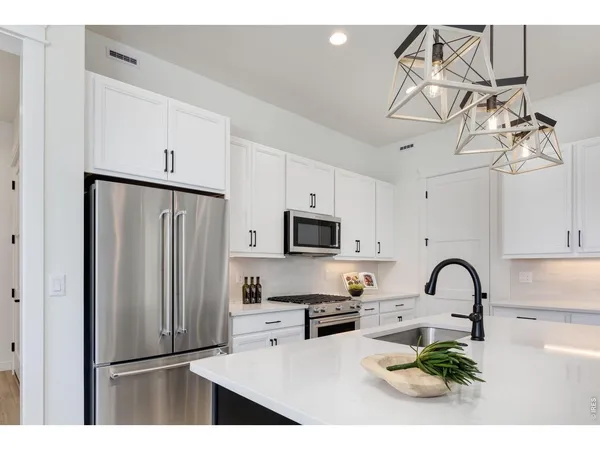 a kitchen with stainless steel appliances granite countertop a sink dishwasher a refrigerator and a stove with wooden floor