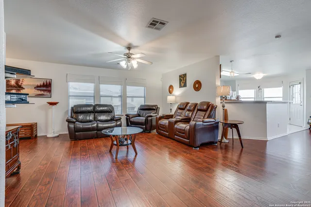a living room with furniture kitchen view and a wooden floor