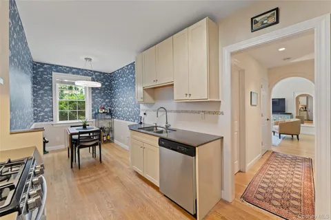 a kitchen with stainless steel appliances granite countertop a stove a sink dishwasher and white cabinets with wooden floor