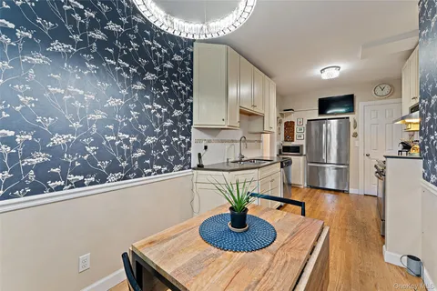 a kitchen with stainless steel appliances a refrigerator a sink a stove and white cabinets with wooden floor