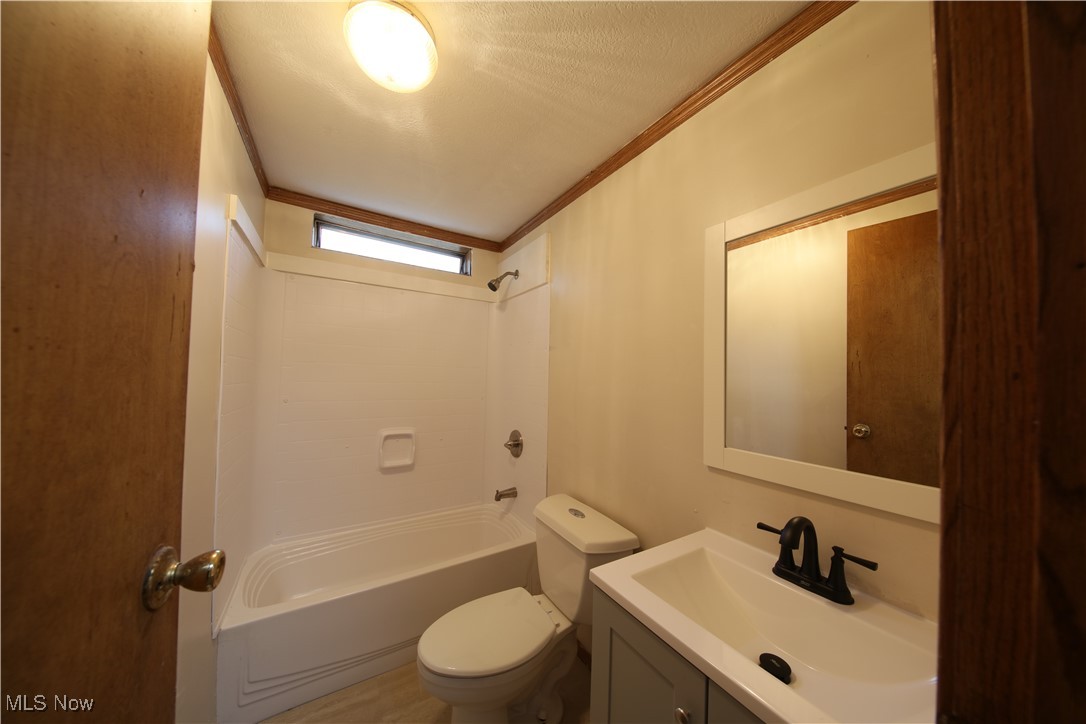 406 Avalon Road Southwest Dellroy, OH 44620 - Photo 21 of 36 Full bathroom with vanity, shower combination, toilet, ornamental molding, and a textured ceiling