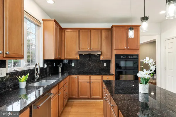 a kitchen with stainless steel appliances granite countertop a sink a stove and a wooden cabinets