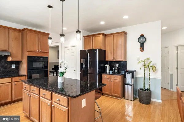 a kitchen with stainless steel appliances granite countertop a refrigerator a stove and a wooden floors