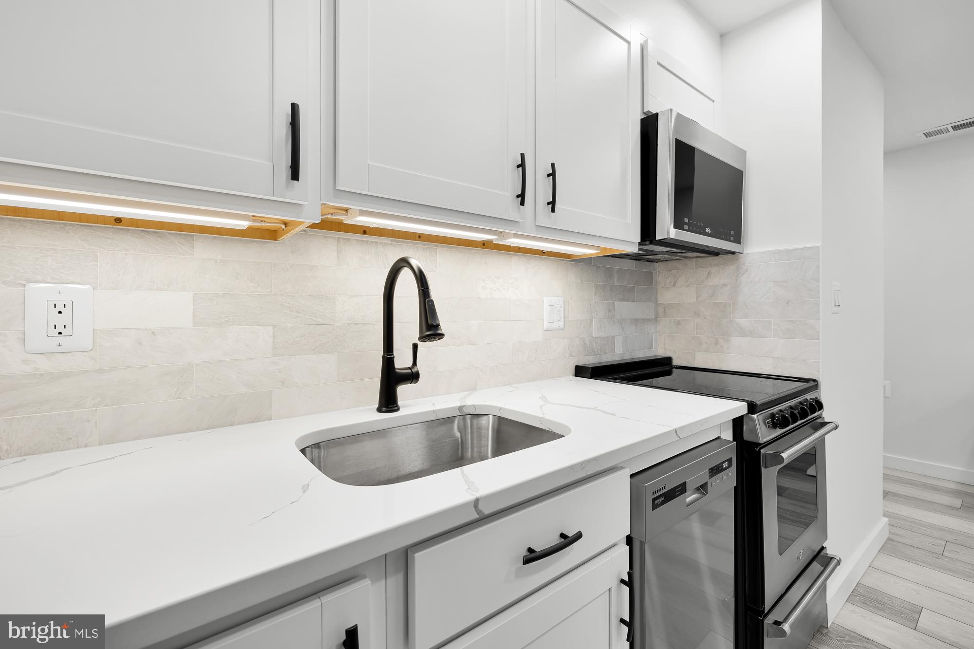 1821 19th Street Northwest, Unit 1 Washington, DC 20009 - Photo 12 of 24 a kitchen with stainless steel appliances granite countertop a sink and a microwave