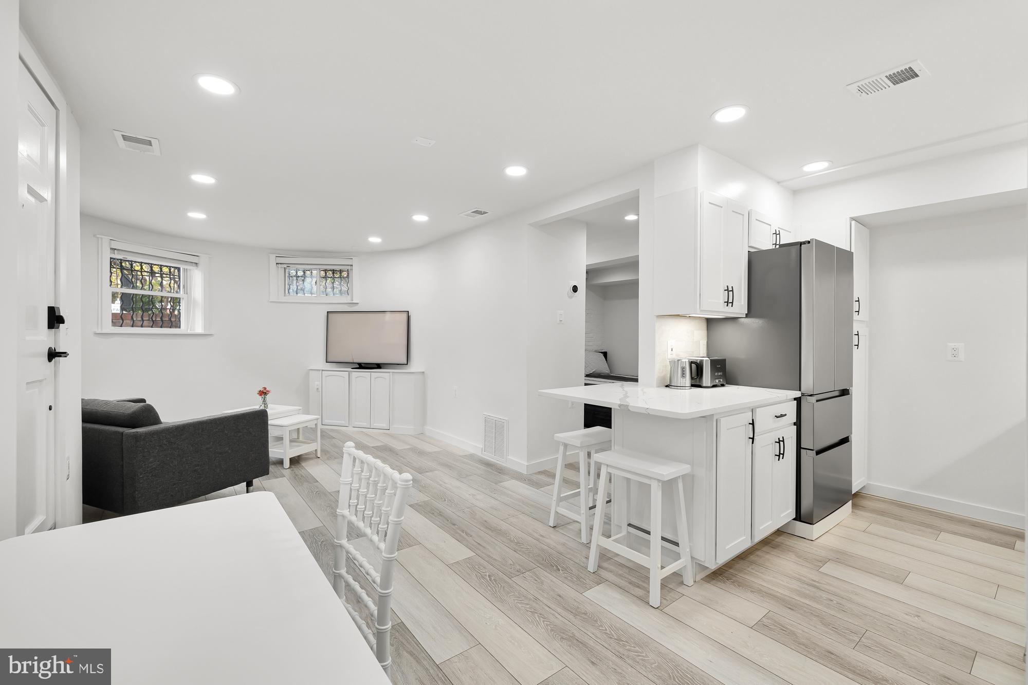 1821 19th Street Northwest, Unit 1 Washington, DC 20009 - Photo 2 of 24 a large white kitchen with stainless steel appliances kitchen island granite countertop a refrigerator and cabinets
