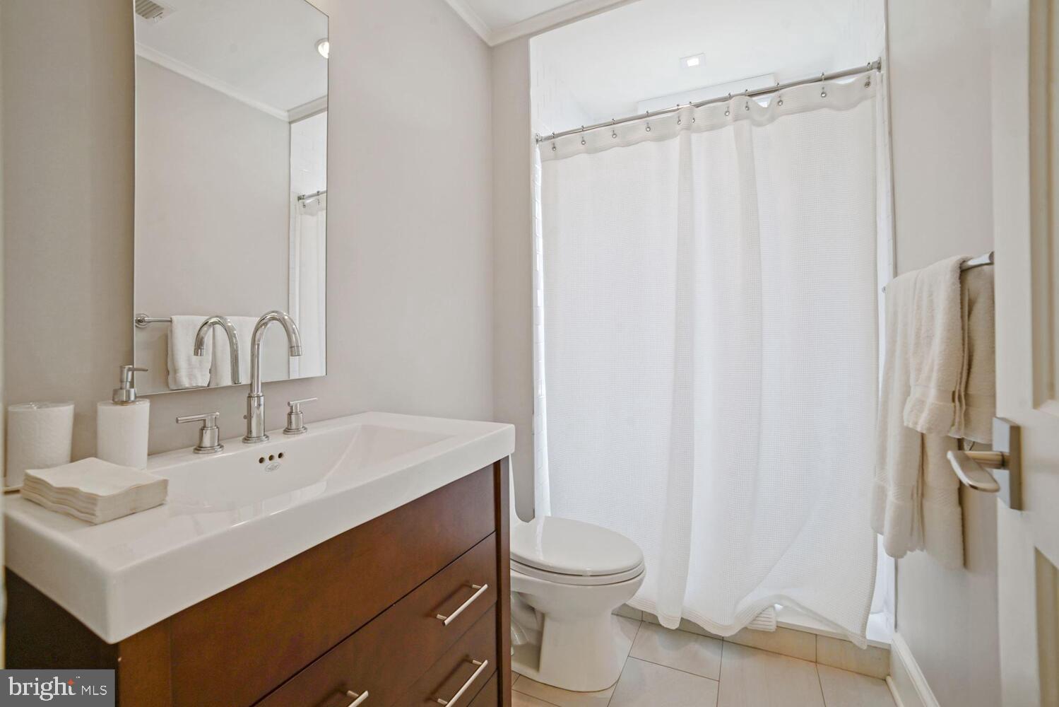 3348 Prospect Street Northwest, Unit 4 Washington, DC 20007 - Photo 8 of 12 a bathroom with a sink a toilet a mirror and shower curtain