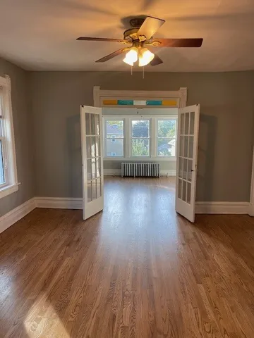 a view of an empty room with wooden floor and a window