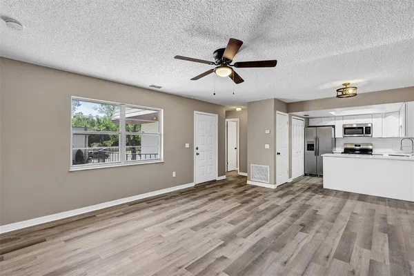 a view of a big room with wooden floor and windows