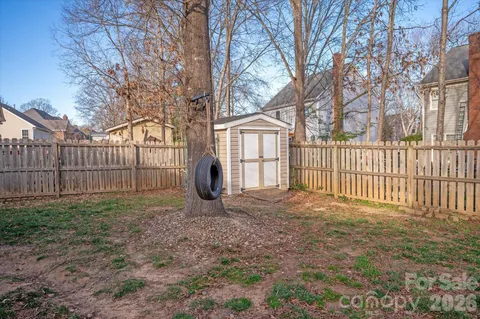 a view of a yard with wooden fence and trees