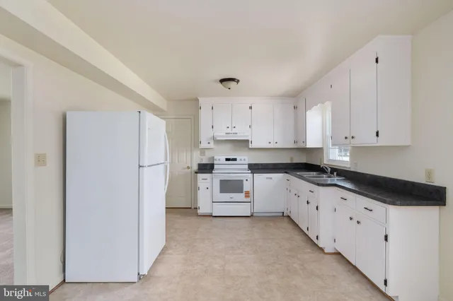 a kitchen with granite countertop white cabinets and refrigerator