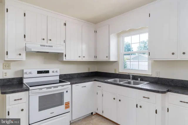 a kitchen with granite countertop white cabinets and white appliances