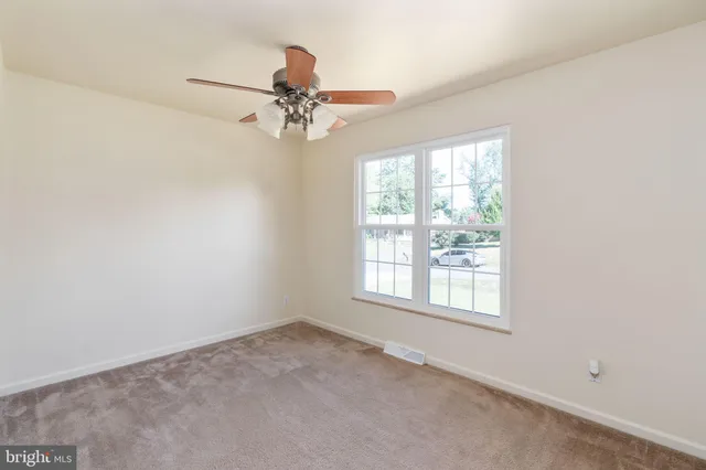 an empty room with a window and a ceiling fan