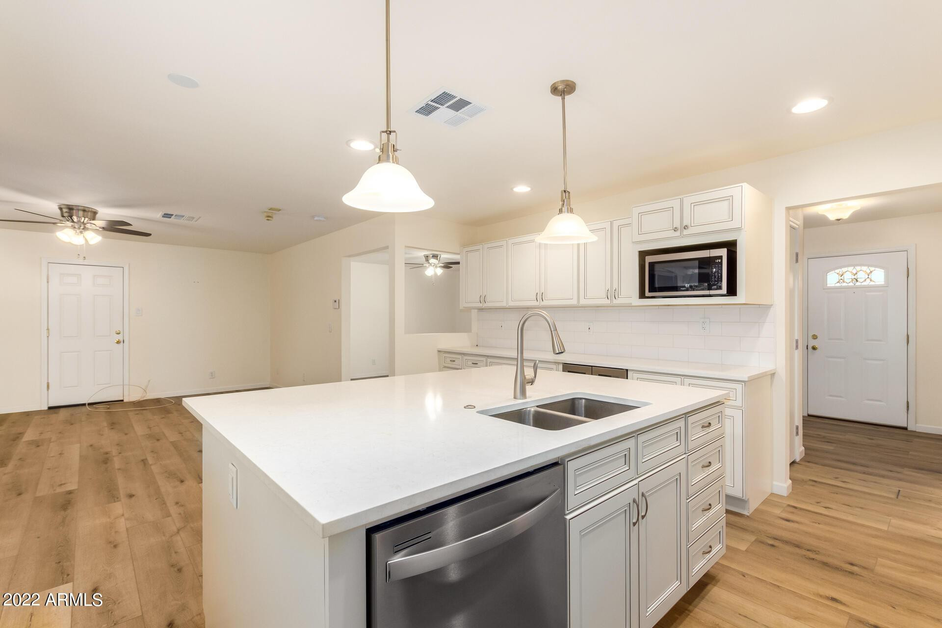 1211 West Hayward Avenue Phoenix, AZ 85021 - Photo 13 of 26 a kitchen that has a sink a microwave a stove and white cabinets with wooden floor