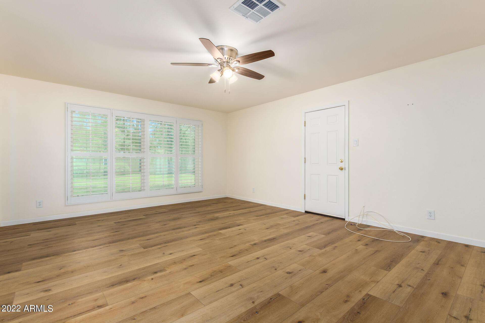 1211 West Hayward Avenue Phoenix, AZ 85021 - Photo 8 of 26 a view of an empty room with wooden floor and a window