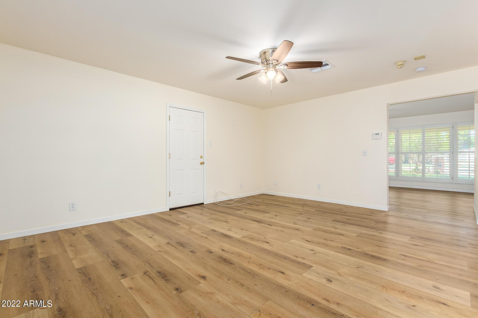 1211 West Hayward Avenue Phoenix, AZ 85021 - Photo 9 of 26 an empty room with wooden floor fan and windows
