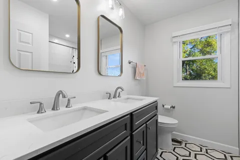 a bathroom with a double vanity sink toilet and a mirror