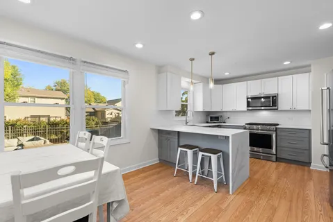 a kitchen with stainless steel appliances granite countertop a stove top oven a sink dishwasher a dining table and chairs with wooden floor