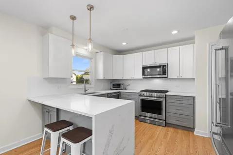 a kitchen with stainless steel appliances granite countertop a stove a sink a refrigerator a stove a dining table and chairs with wooden floor