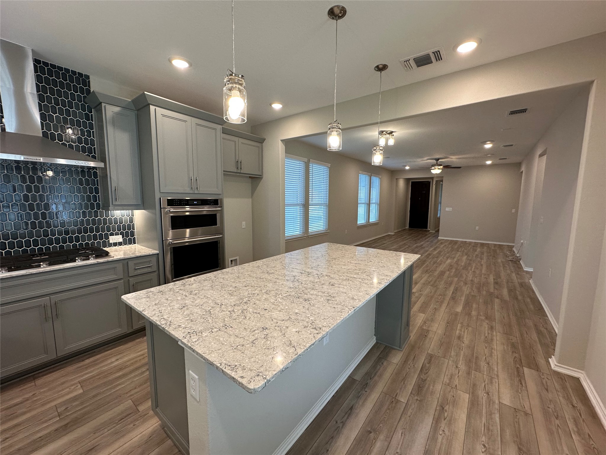 219 Coachsmith Street Georgetown, TX 78633 - Photo 11 of 25 Kitchen featuring gas cooktop, gray cabinetry, stainless steel double oven, visible vents, and wall chimney exhaust hood