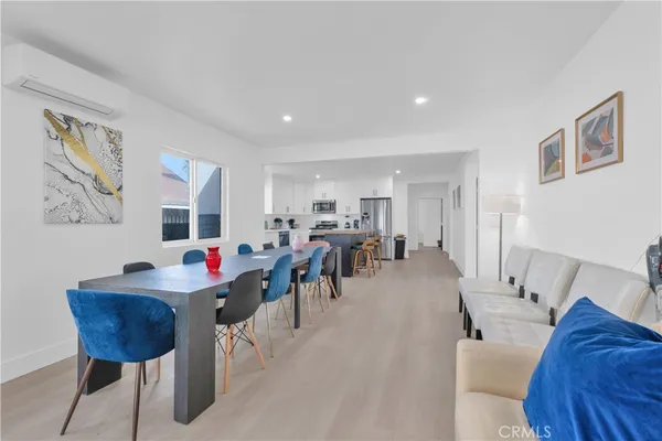 a living room with furniture and a dining table with wooden floor