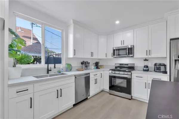 a kitchen with cabinets stainless steel appliances a sink a window and white cabinets