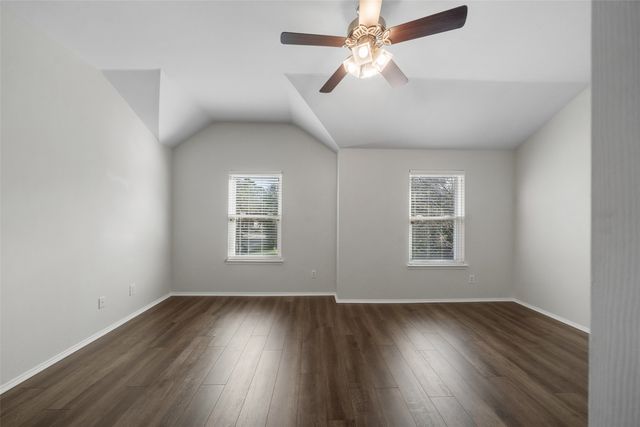 an empty room with wooden floor ceiling fan and windows