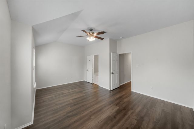 an empty room with wooden floor and a ceiling fan