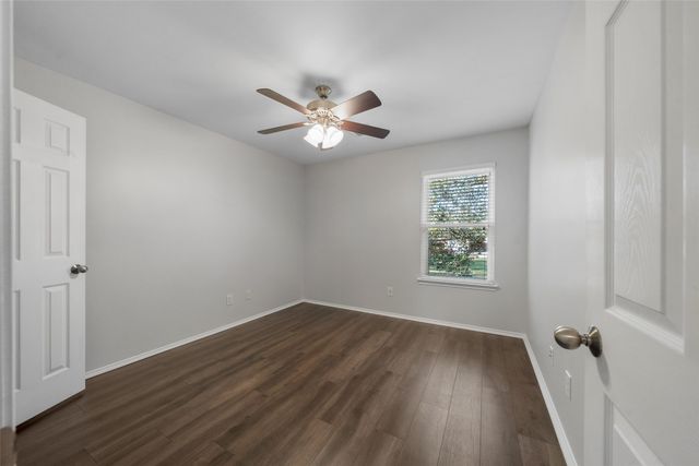 a view of a room with wooden floor and a ceiling fan