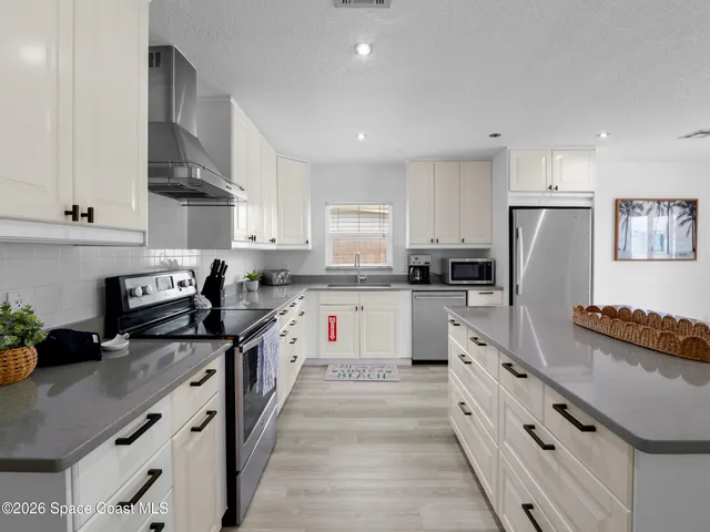 a kitchen with stainless steel appliances kitchen island granite countertop a stove a sink a refrigerator and white cabinets