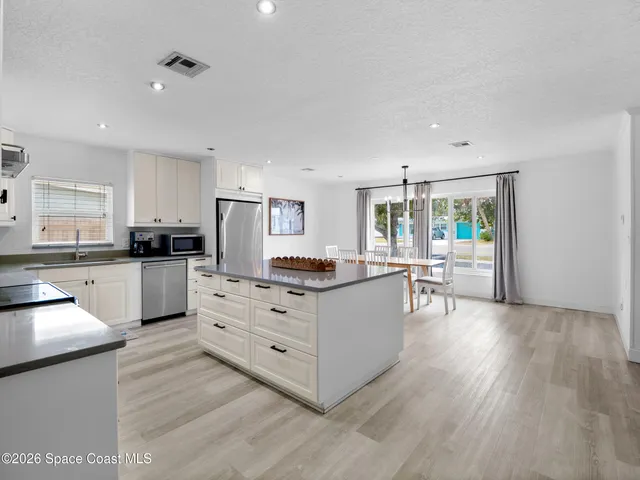 a view of open kitchen with white cabinets and stainless steel appliances