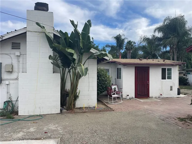 a view of a house with potted plants and a large tree