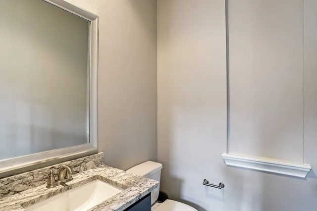 a bathroom with a granite countertop sink and a toilet