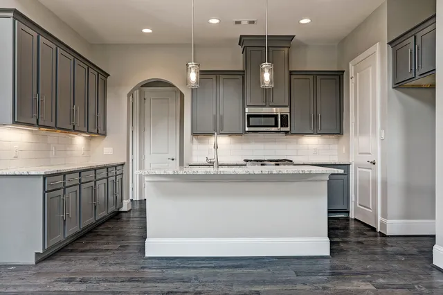 a kitchen with stainless steel appliances granite countertop a sink dishwasher a stove and a refrigerator with wooden floor