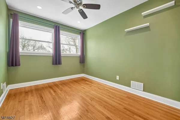 a view of an empty room with a window and a ceiling fan