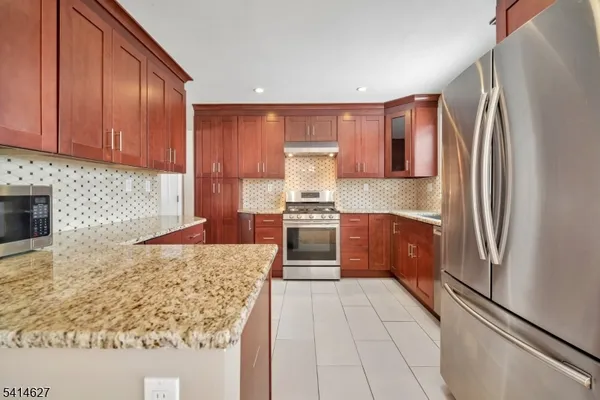 a kitchen with granite countertop a refrigerator and a stove top oven